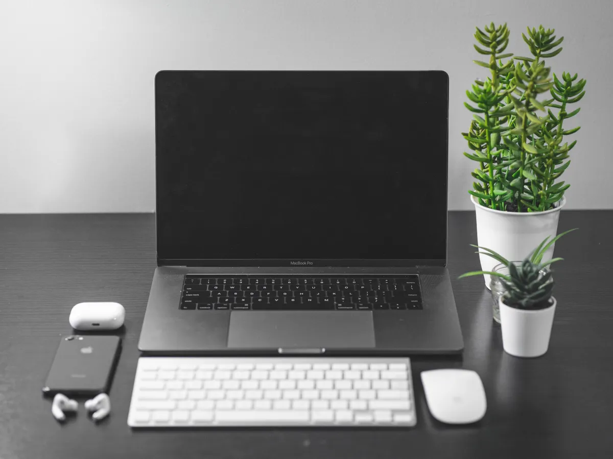 Tidy desk with a laptop, keyboard, mouse and potted plants